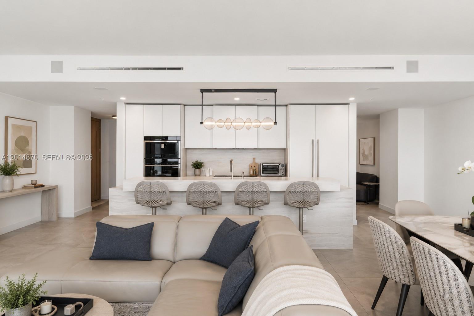 A modern open-concept kitchen features white cabinetry, a stone island with bar seating, and pendant lighting — 900 N Ocean Blvd # 1903, Pompano Beach FL 33062, POMPANO BEACH, FL