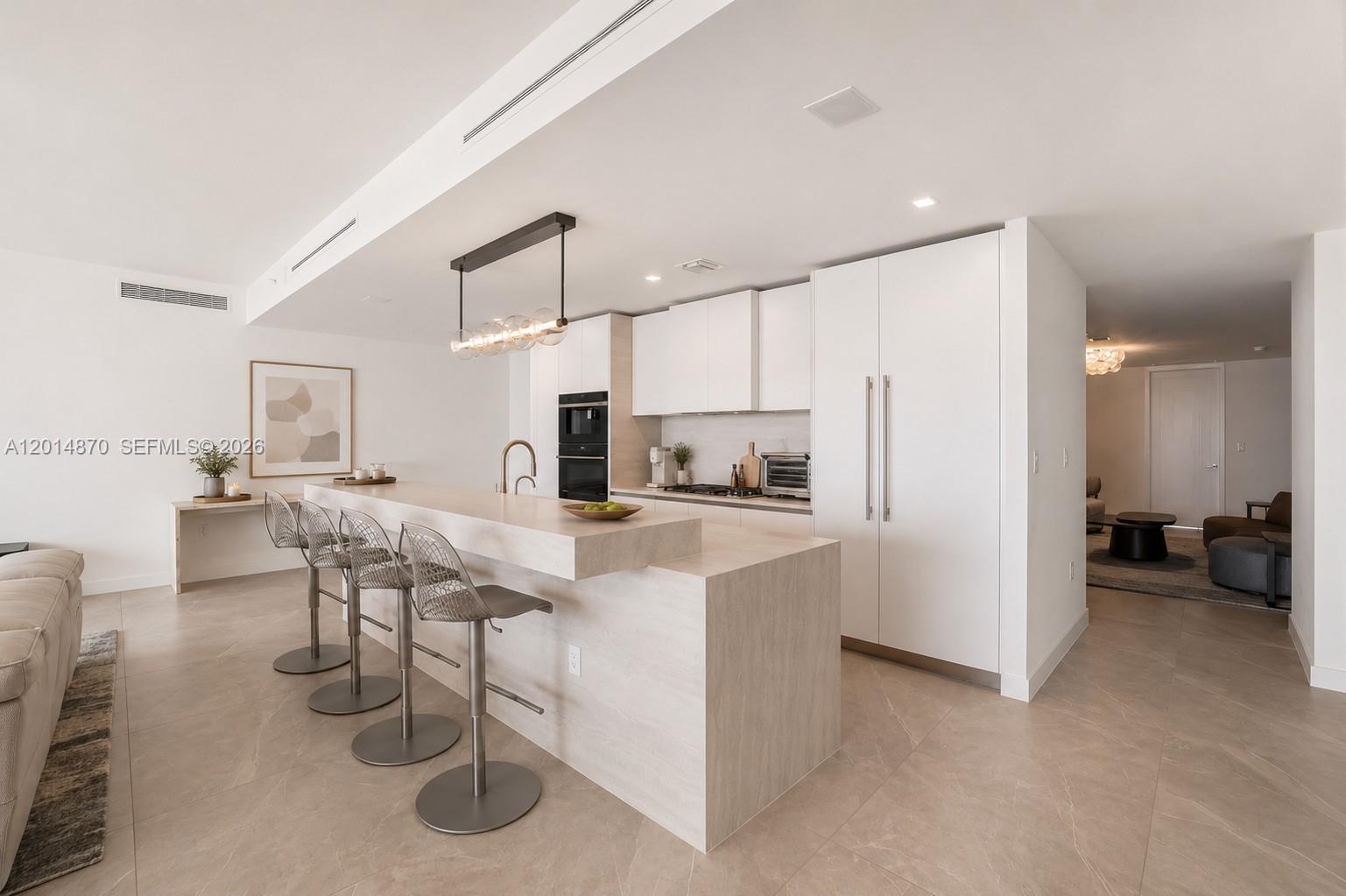 A modern kitchen features a stone waterfall island, white cabinetry, and bar seating — 900 N Ocean Blvd # 1903, Pompano Beach FL 33062, POMPANO BEACH, FL