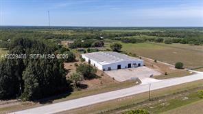 An aerial view shows a white industrial warehouse building situated on a large rural lot — 14961 W State Road 78, Moore Haven FL 33471, MOORE HAVEN, FL