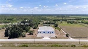 An aerial view shows a large metal warehouse building situated on a rural, grassy lot — 14961 W State Road 78, Moore Haven FL 33471, MOORE HAVEN, FL