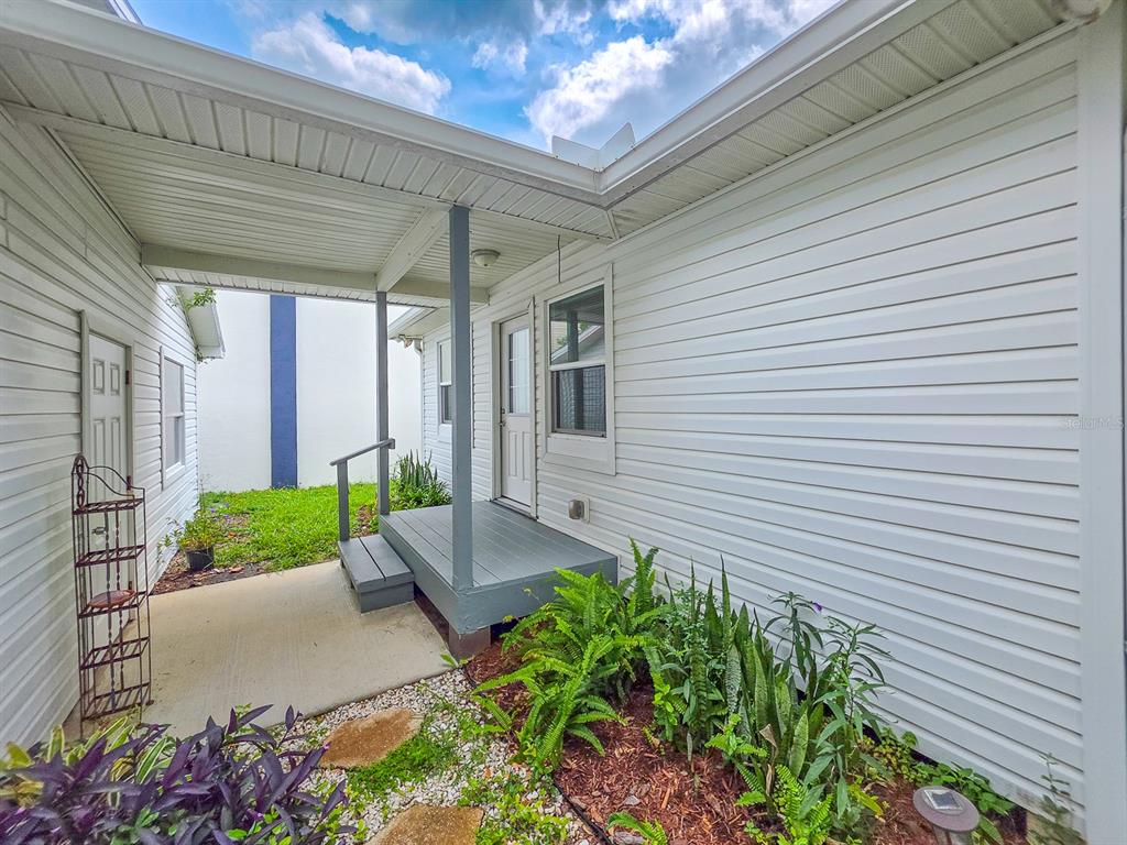 A white-sided house exterior features a small wooden porch, a concrete walkway, and garden beds — 216 S 5TH STREET UNIT B, FLAGLER BEACH, FL