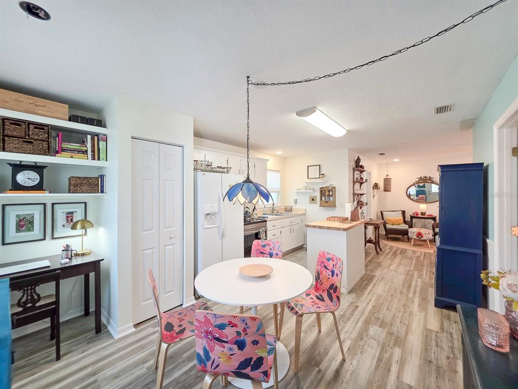 A kitchen and dining area features a white round table, floral chairs, and wood-look flooring — 216 S 5TH STREET UNIT B, FLAGLER BEACH, FL