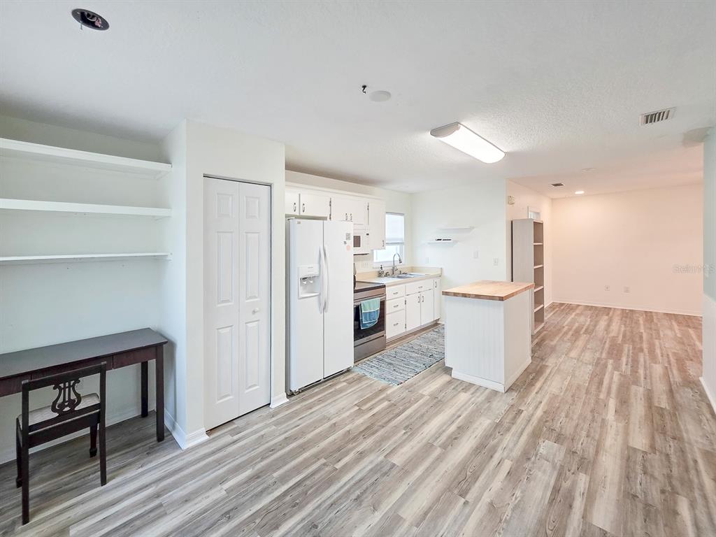 A kitchen with white cabinets, a refrigerator, a small island, and wood-look flooring — 216 S 5TH STREET UNIT B, FLAGLER BEACH, FL