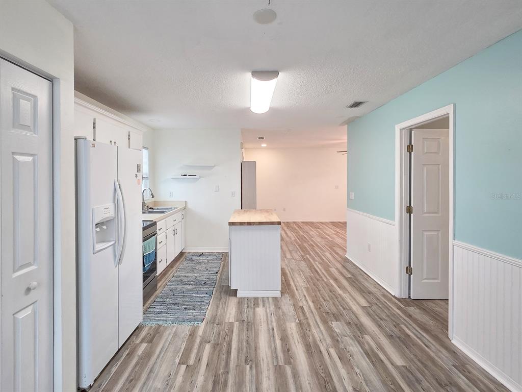 A kitchen with white cabinets, a central island, and light blue walls with white wainscoting — 216 S 5TH STREET UNIT B, FLAGLER BEACH, FL