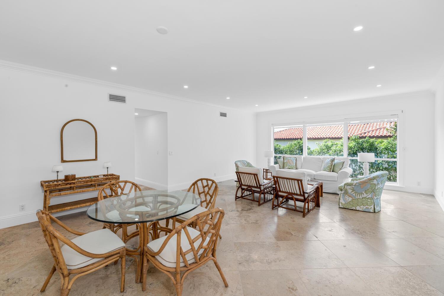 A bright, open-concept living and dining area features rattan furniture, tile flooring, and large windows — 350 Cocoanut Row # 3a, Palm Beach FL 33480, PALM BEACH, FL