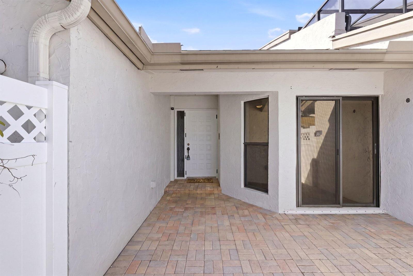 A paved entryway leads to a white front door and a sliding glass door — 6670 Canary Palm Circle Unit 16, Boca Raton FL 33433, BOCA RATON, FL