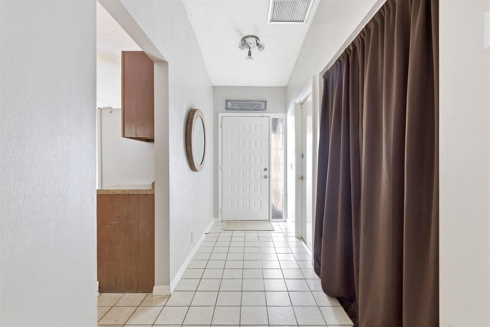 A tiled entryway features a white front door, brown curtains, and a wall-mounted mirror — 6670 Canary Palm Circle Unit 16, Boca Raton FL 33433, BOCA RATON, FL