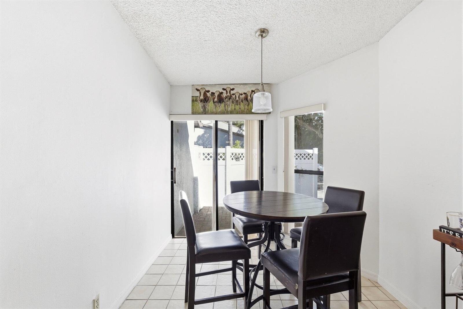 A dining area features a round table, four chairs, tile flooring, and a sliding glass door — 6670 Canary Palm Circle Unit 16, Boca Raton FL 33433, BOCA RATON, FL