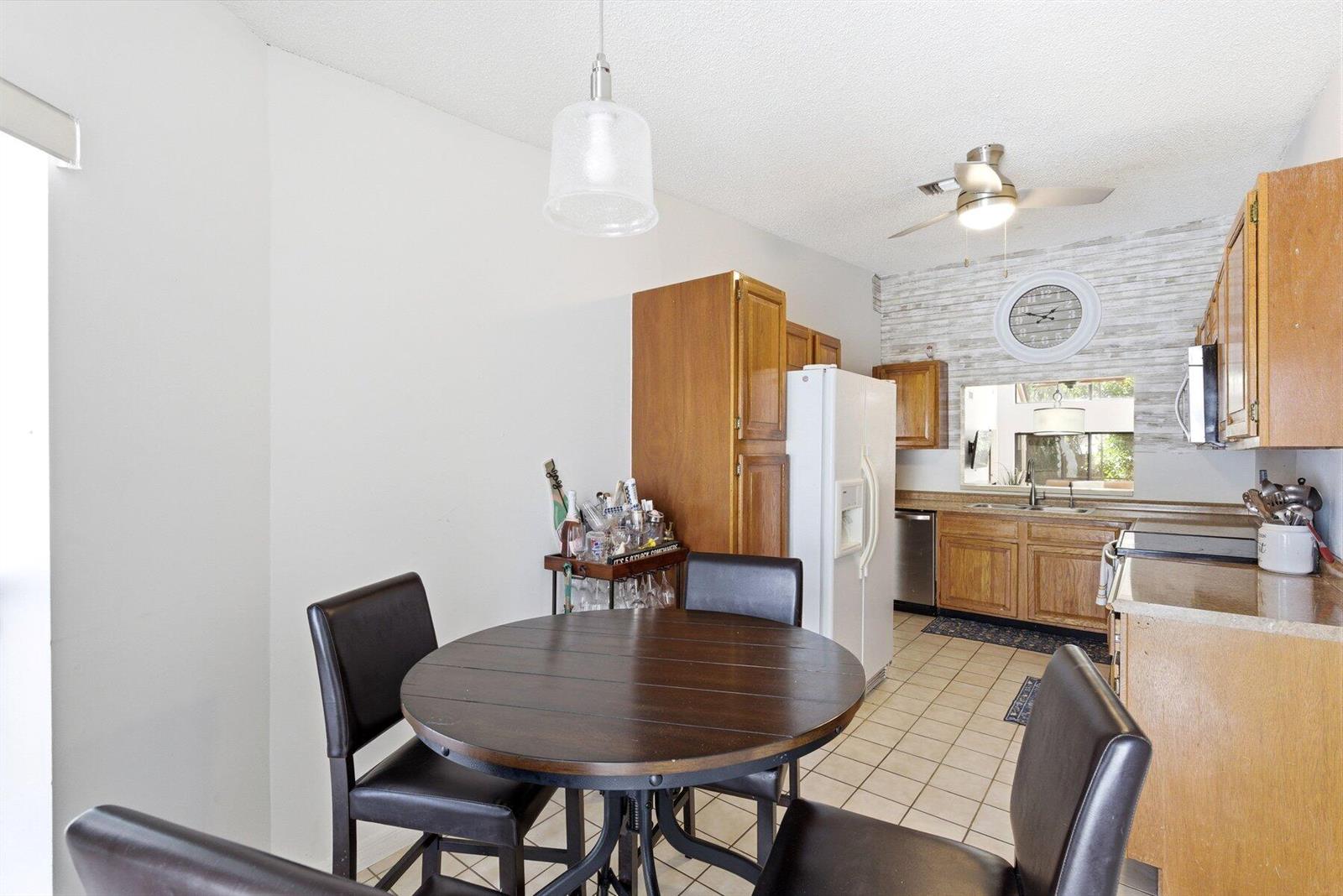 A kitchen features wooden cabinets, a round dining table, and a white refrigerator — 6670 Canary Palm Circle Unit 16, Boca Raton FL 33433, BOCA RATON, FL
