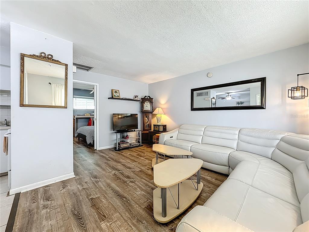 A living room features a white sectional sofa, wood-look flooring, and a grandfather clock — 250 ROSERY ROAD NW UNIT 228, LARGO, FL