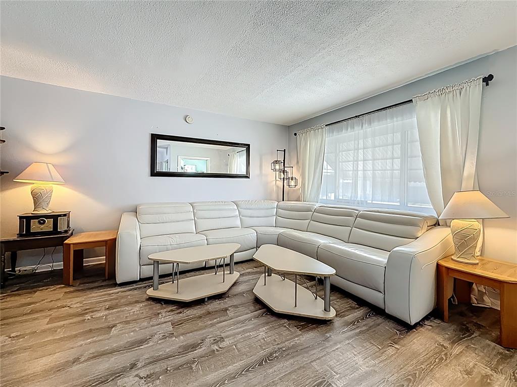 A living room features a white sectional sofa, two tiered coffee tables, and wood-look flooring — 250 ROSERY ROAD NW UNIT 228, LARGO, FL
