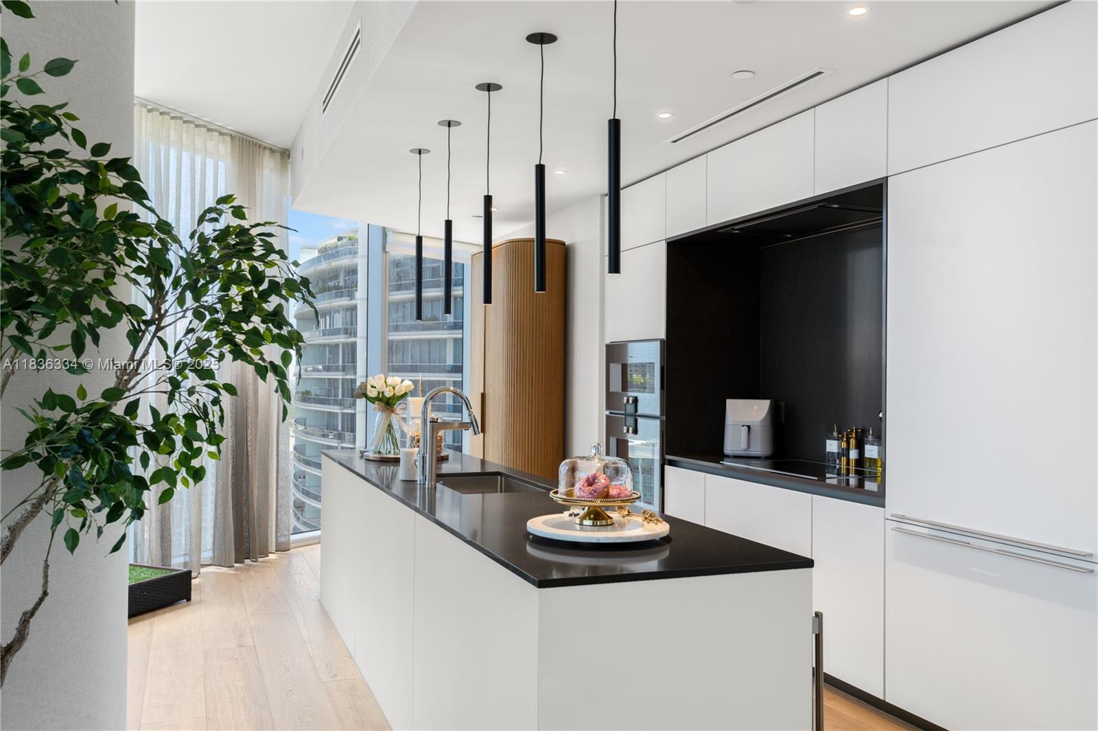 A modern kitchen features a white island with a black countertop and pendant lighting — 300 Biscayne Blvd way # 4707, Miami FL 33131, MIAMI, FL
