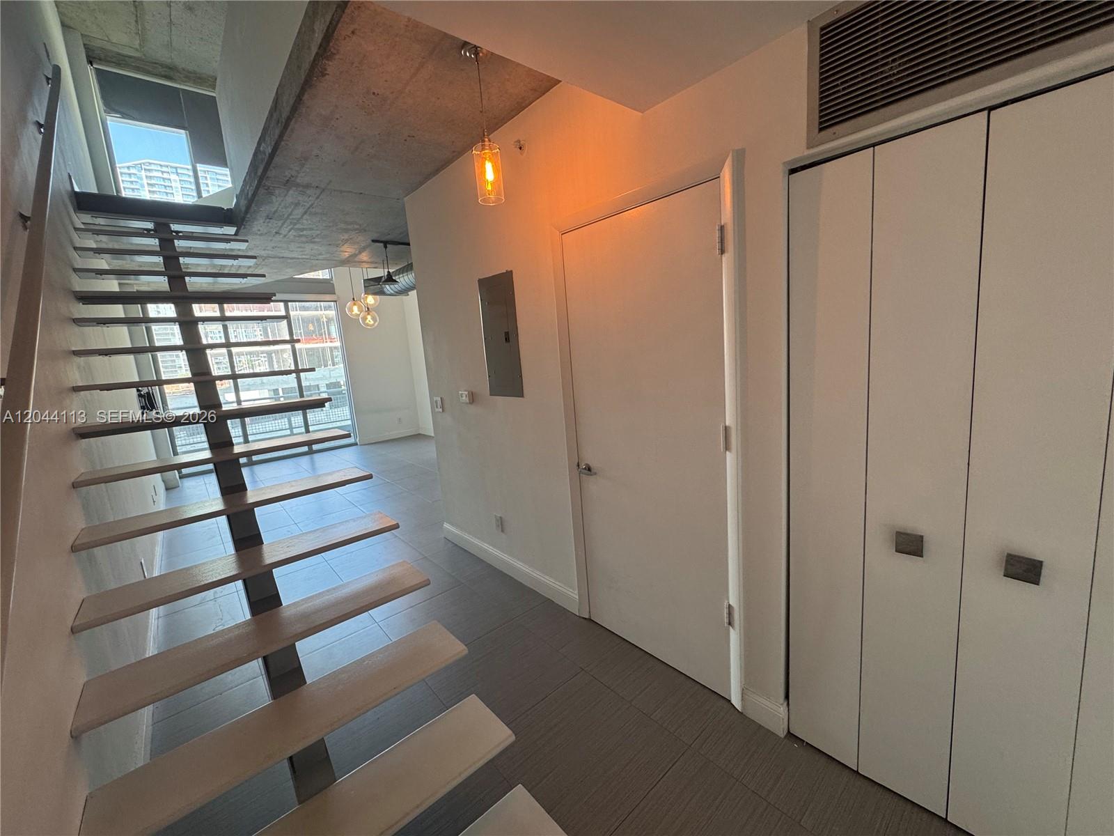 An interior view shows a staircase with wooden treads, a concrete ceiling, and tiled floors — 690 SW 1st Ct # 1516, Miami FL 33130, MIAMI, FL