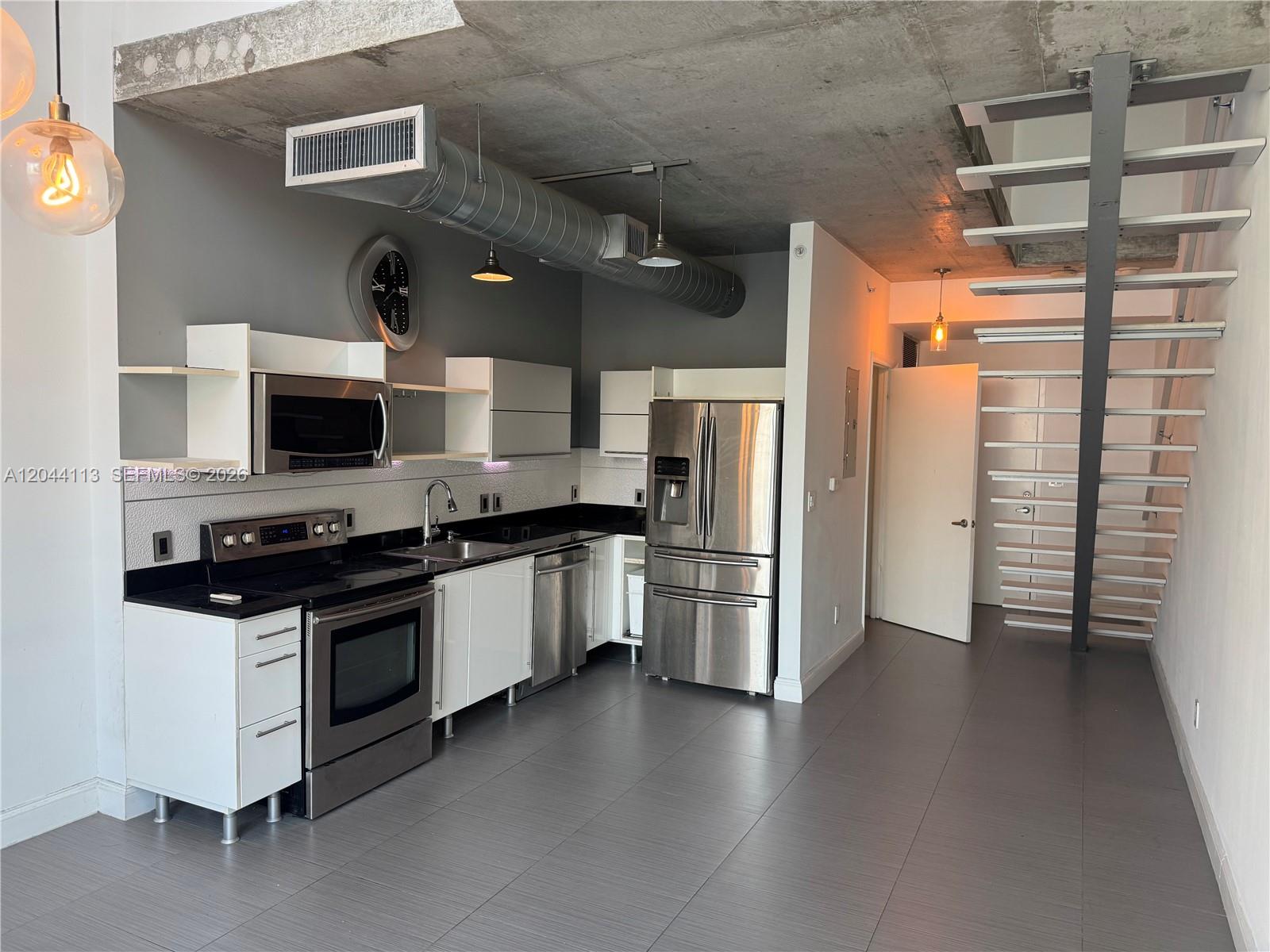 A modern kitchen features stainless steel appliances, white cabinetry, and an exposed concrete ceiling — 690 SW 1st Ct # 1516, Miami FL 33130, MIAMI, FL