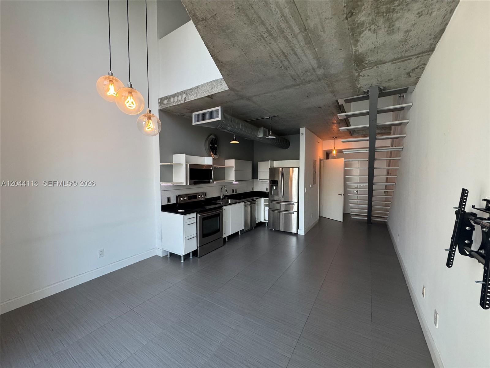 A modern kitchen features white cabinetry, stainless steel appliances, and a raw concrete ceiling — 690 SW 1st Ct # 1516, Miami FL 33130, MIAMI, FL