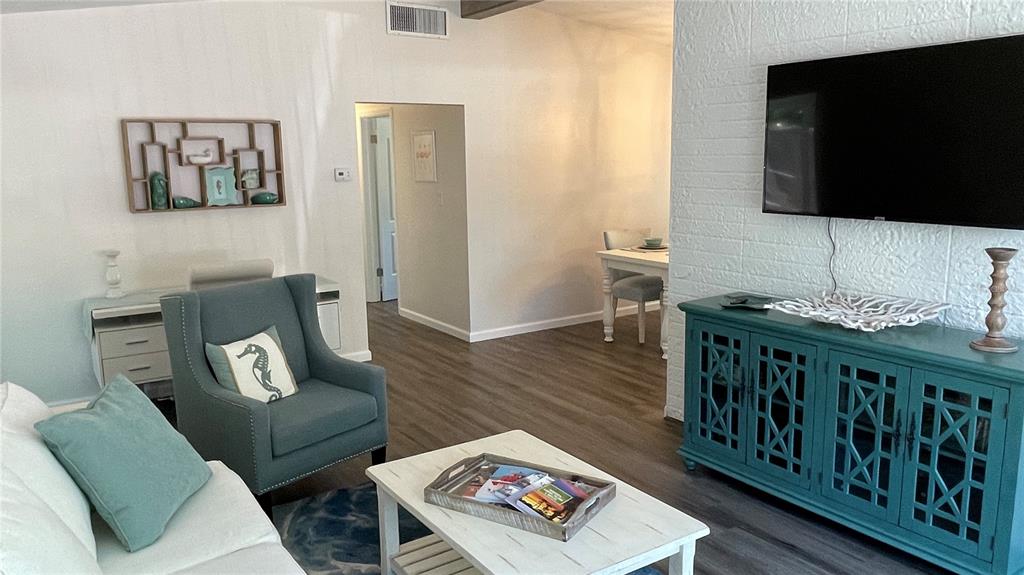 A living room features a blue armchair, a white coffee table, and a teal media console — 2504 S MILMAR DRIVE, SARASOTA, FL