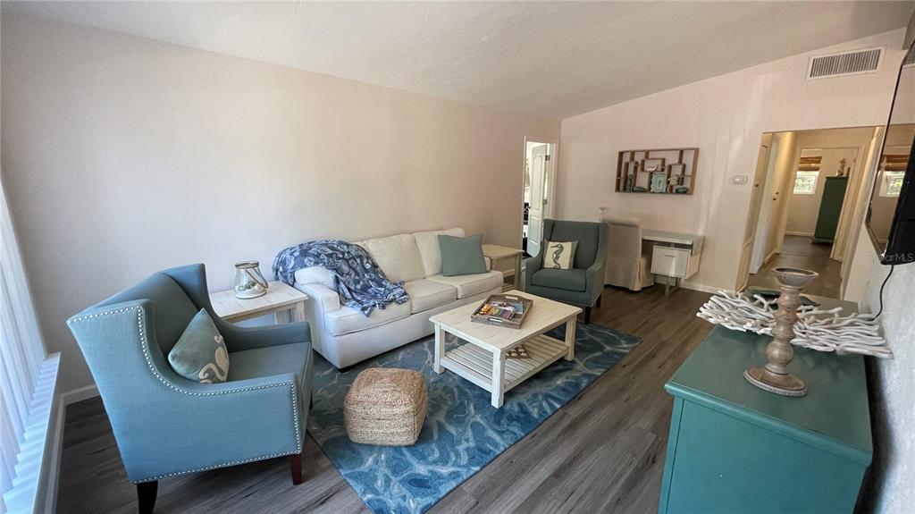 A living room features a white sofa, blue armchairs, a coffee table, and wood-look flooring — 2504 S MILMAR DRIVE, SARASOTA, FL