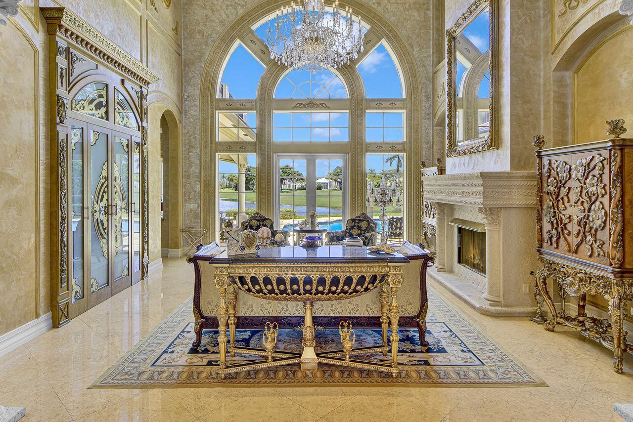 A grand, ornate office features a large desk, fireplace, and floor-to-ceiling windows overlooking a pool — 17730 Scarsdale Way, Boca Raton FL 33496, BOCA RATON, FL