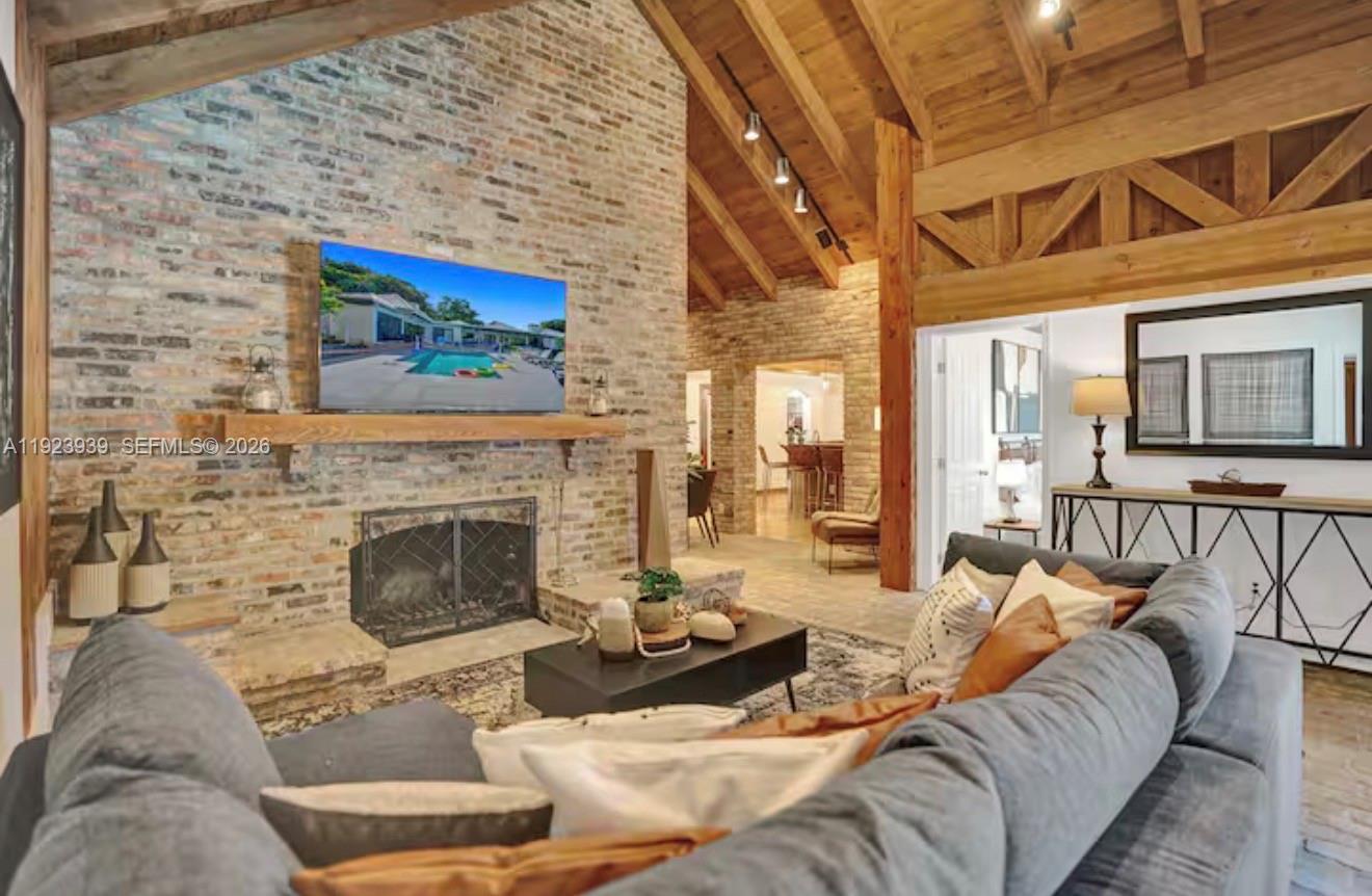 A living room features a brick fireplace, vaulted wood-beam ceiling, and a gray sectional sofa — 11155 SW 40th St, Davie FL 33328, DAVIE, FL