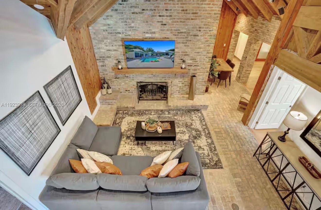 A high-angle view of a living room with a brick fireplace, vaulted ceiling, and sectional sofa — 11155 SW 40th St, Davie FL 33328, DAVIE, FL