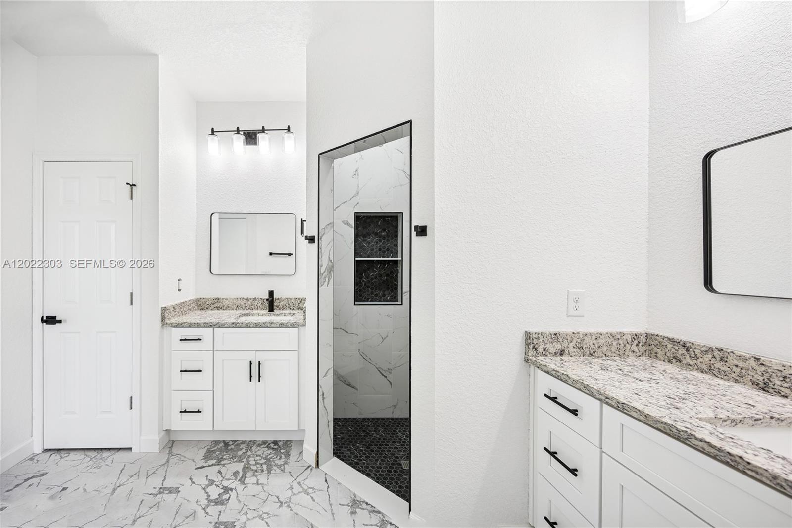 A modern bathroom features dual white vanities with granite countertops and a walk-in shower — 7433 DOMENICO ST, Sebring FL 3872, SEBRING, FL