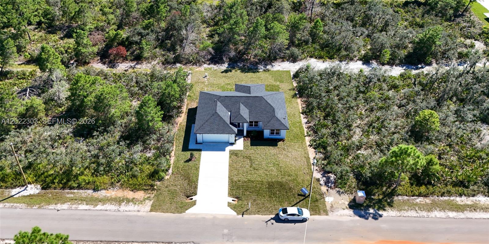 An aerial view shows a single-story house with a dark roof and a concrete driveway — 7433 DOMENICO ST, Sebring FL 3872, SEBRING, FL