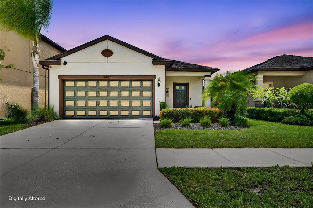 A single-story house with a two-car garage, a concrete driveway, and a landscaped front yard — 1407 CUSTER BAYOU STREET, RUSKIN, FL