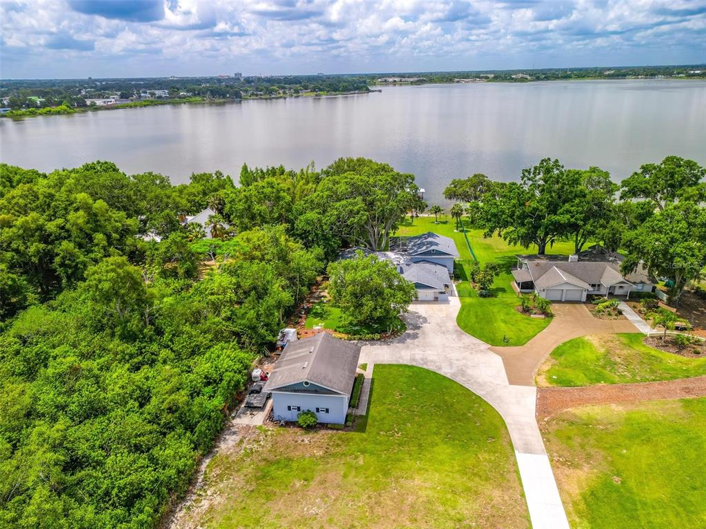An aerial view shows a house with a detached garage, large lawn, and lakefront access — 250 BRIGHAM ROAD NW, WINTER HAVEN, FL