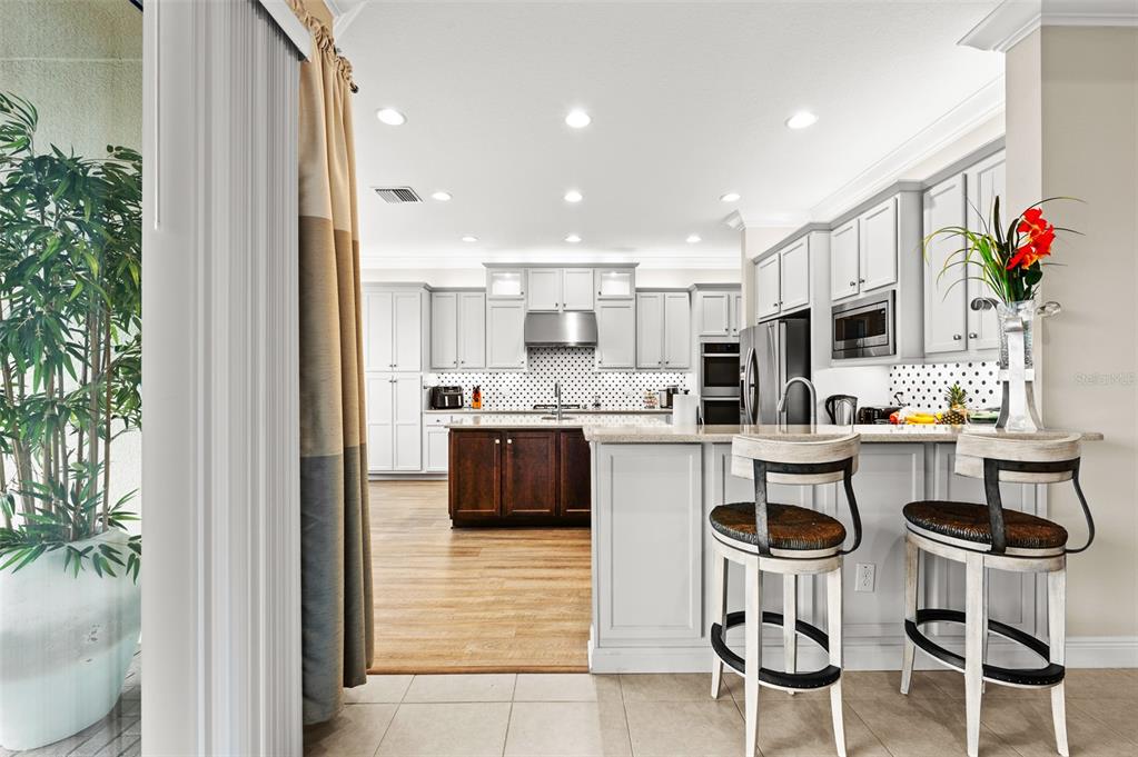 A kitchen features white cabinets, a dark wood island, and a breakfast bar with stools — 30715 TUMBLEBERRY STREET, WESLEY CHAPEL, FL