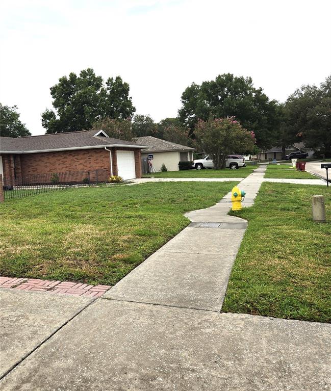 A view of a suburban street featuring a brick house, sidewalk, and yellow fire hydrant — 812 SANDALWOOD DRIVE, PLANT CITY, FL