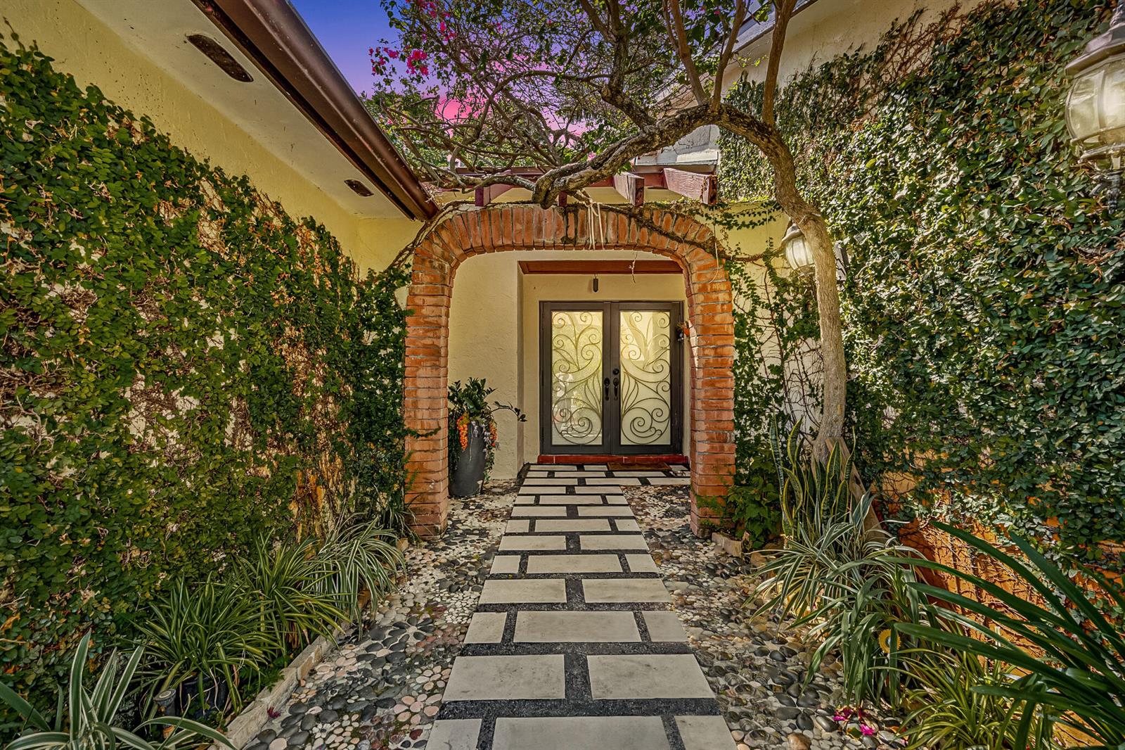 A stone walkway leads through a brick archway toward a house entrance with glass doors — 5441 SW 155th Place, Miami FL 33185, MIAMI, FL