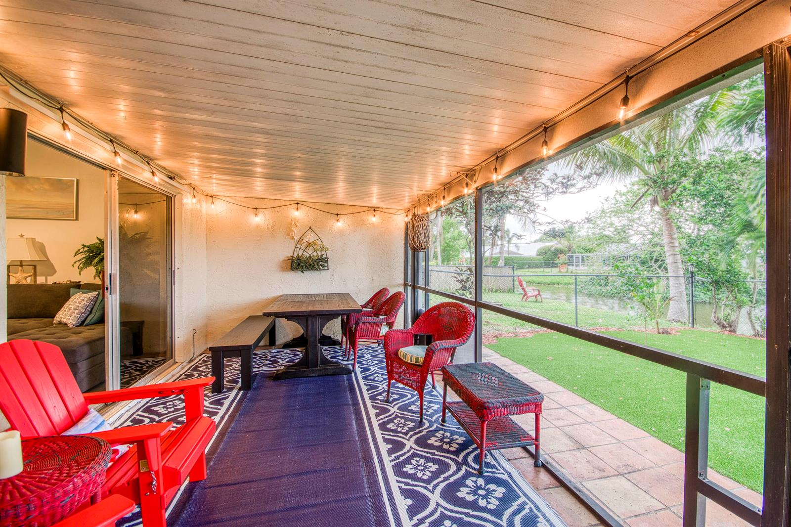 A screened-in patio features red wicker chairs, a dining table, and views of a yard — 178 Pinewood Court, Jupiter FL 33458, JUPITER, FL
