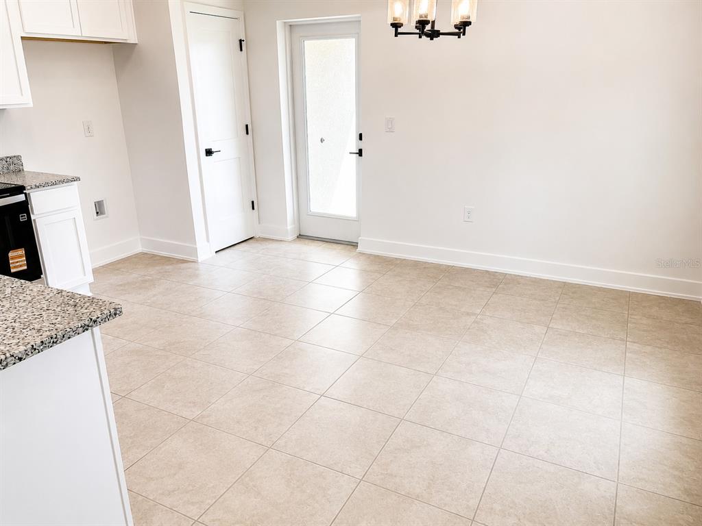 A kitchen and dining area with tile flooring, white cabinets, granite countertops, and a glass door — 7569 BENT TREE LOOP, ST CLOUD, FL
