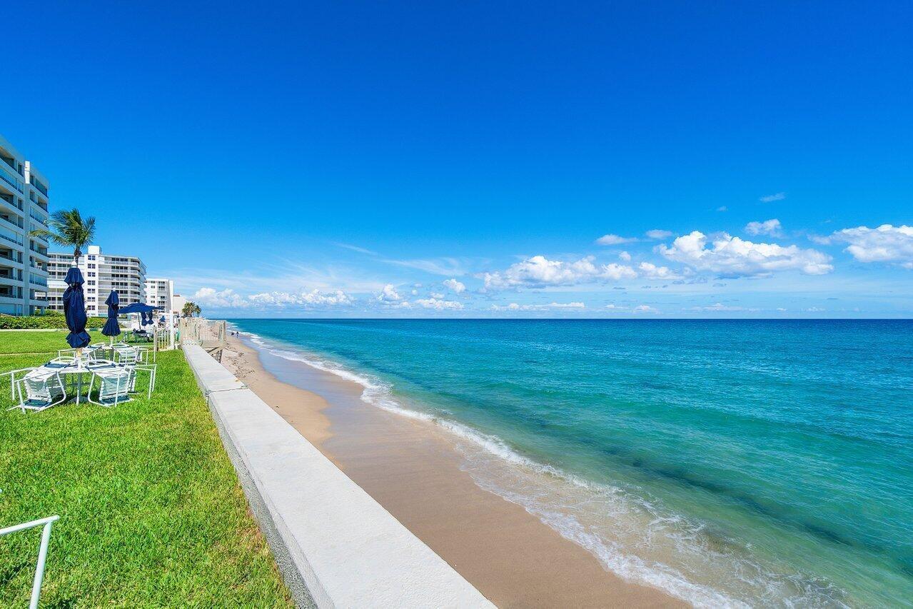 A grassy lawn with patio furniture sits next to a sandy beach and the ocean — 3570 S Ocean Boulevard # 806, Palm Beach FL 33480, PALM BEACH, FL