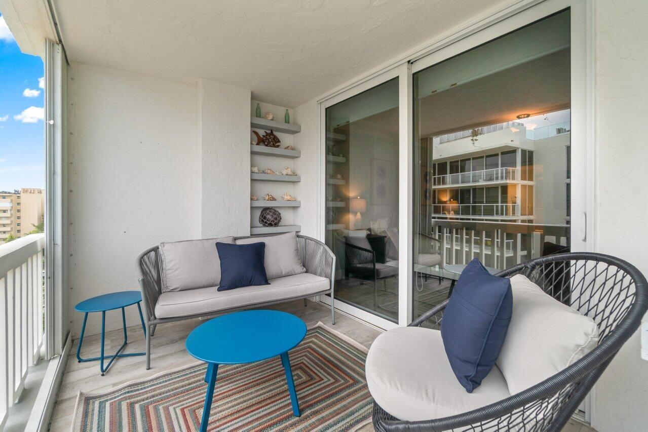 A balcony features a gray sofa, a round blue table, and a wicker accent chair — 3570 S Ocean Boulevard # 806, Palm Beach FL 33480, PALM BEACH, FL