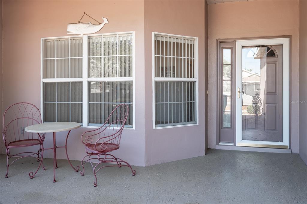 A covered patio features a small table with two metal chairs and a glass door — 9077 SW 95TH AVENUE, OCALA, FL