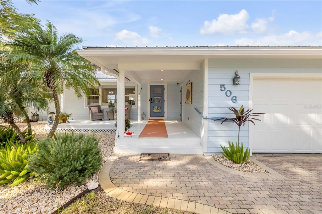 The exterior of a light blue house features a covered porch, brick walkway, and garage — 506 YUPON AVENUE, NEW SMYRNA BEACH, FL
