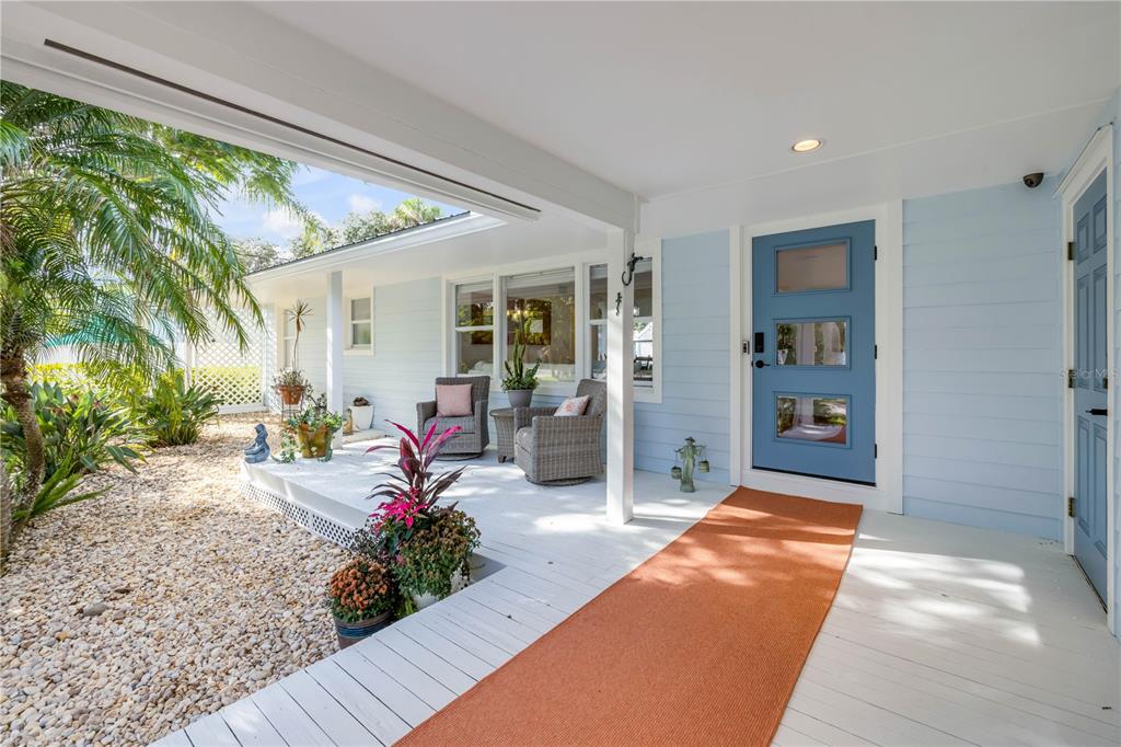 A light blue house exterior features a white porch with wicker chairs and a rug — 506 YUPON AVENUE, NEW SMYRNA BEACH, FL