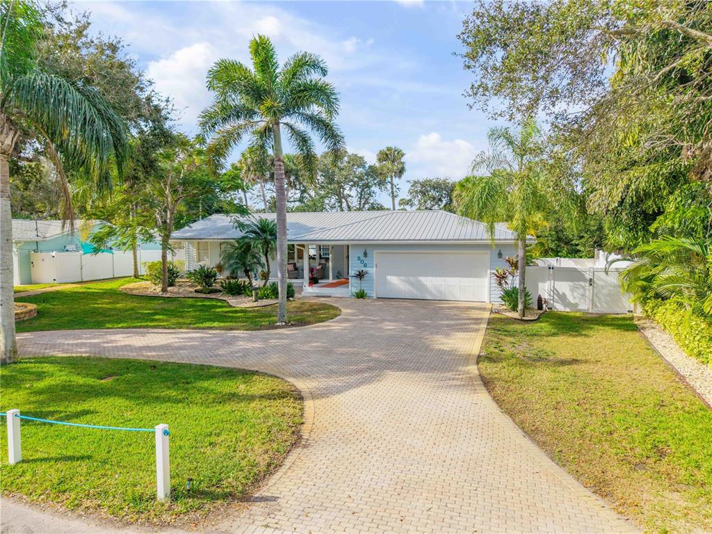 A light blue single-story house with a metal roof and a paved driveway — 506 YUPON AVENUE, NEW SMYRNA BEACH, FL