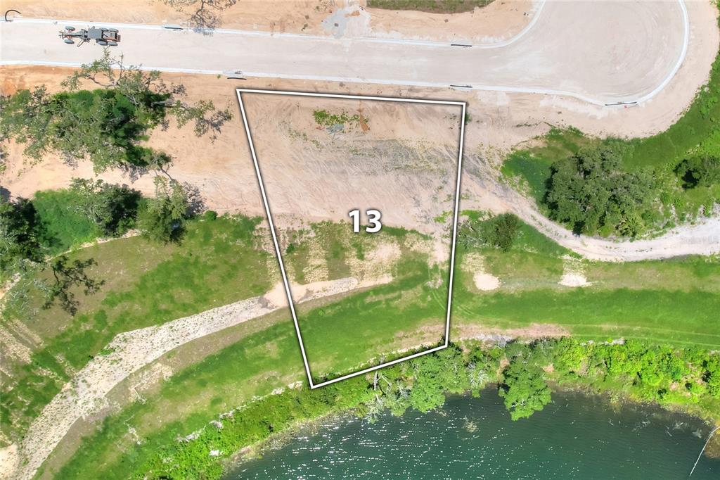An aerial view shows a vacant lot marked with the number 13 near a lake — 145 TRANQUIL MIRROR LAKE COURT Lot 13, CLERMONT, FL