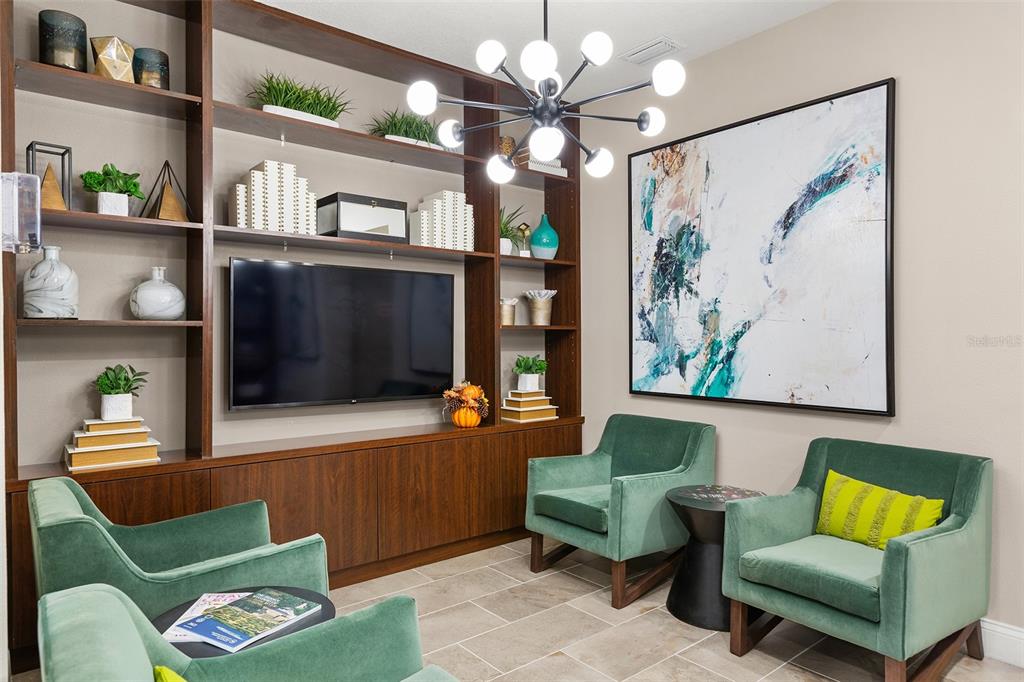 A living room features built-in wooden shelving, a television, and three green velvet armchairs — 7505 LAUREATE BLVD UNIT 2208, ORLANDO, FL