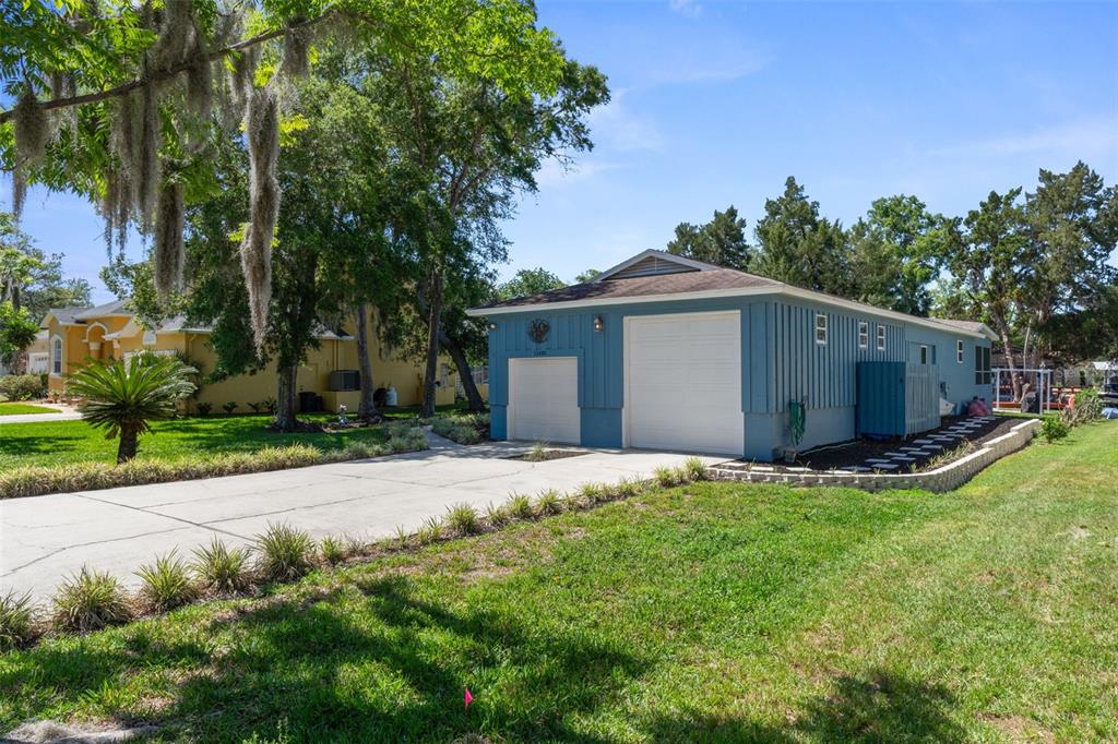 A blue detached garage with two white doors sits next to a concrete driveway — 11430 W WATERWAY DRIVE, HOMOSASSA, FL