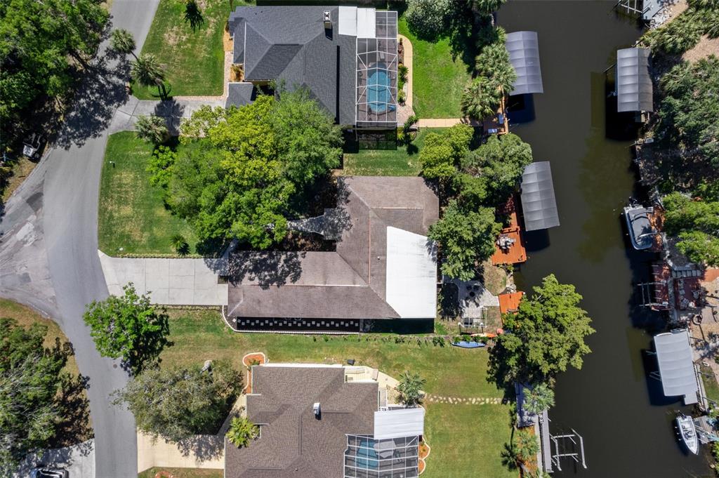An aerial view shows a house with a large roof, driveway, and backyard facing a canal — 11430 W WATERWAY DRIVE, HOMOSASSA, FL