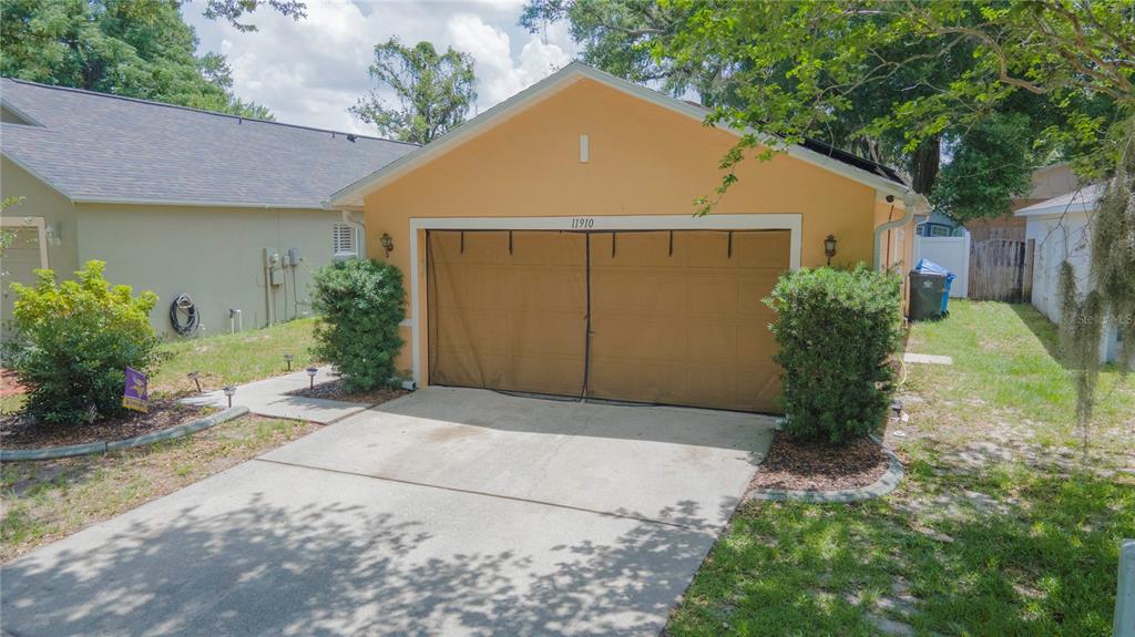 A tan detached garage with a brown screen cover over the double door entrance — 11910 MANGO GROVES BOULEVARD, SEFFNER, FL