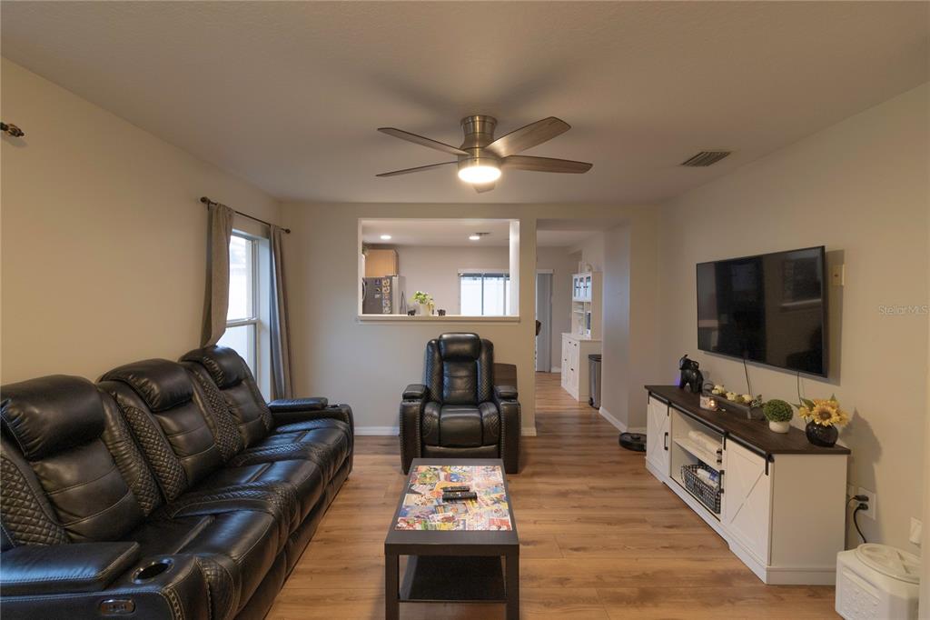 A living room features a dark leather sofa, a recliner, a coffee table, and television — 11910 MANGO GROVES BOULEVARD, SEFFNER, FL
