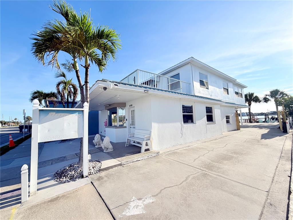 A white two-story building with a flat roof, balcony, and palm trees sits near a road — 17729 GULF BOULEVARD, REDINGTON SHORES, FL