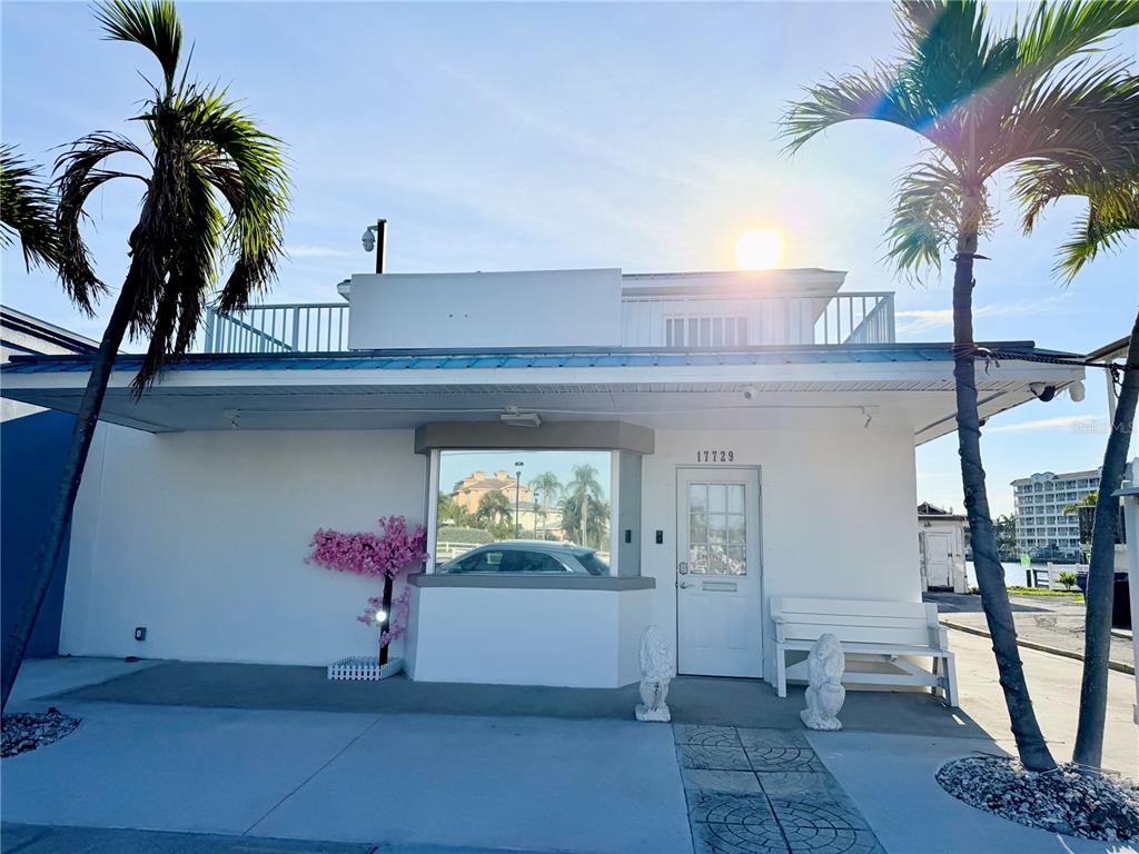 A white building exterior features a front door, a large window, and two palm trees — 17729 GULF BOULEVARD, REDINGTON SHORES, FL