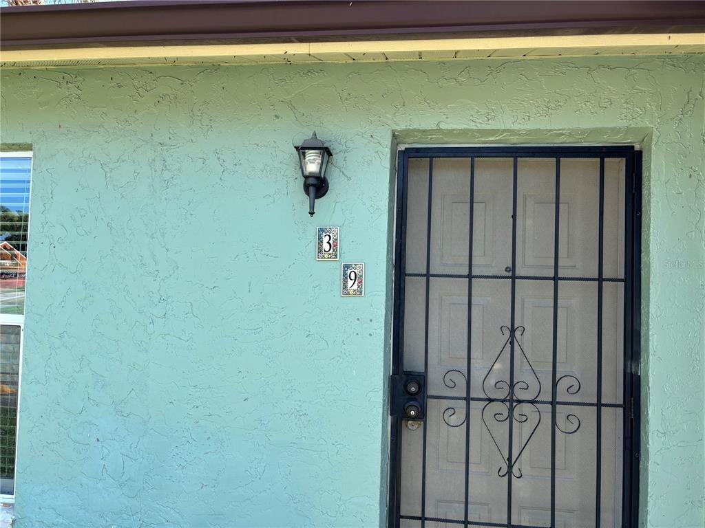 A light green exterior wall features a house number 39 and a black security door — 39 LAGO MESA WAY, KISSIMMEE, FL