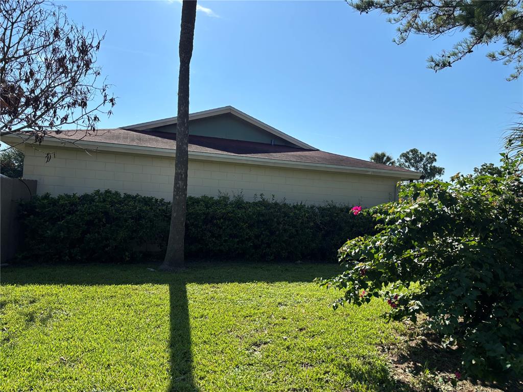 A view of a house exterior with a block wall, a hedge, and a lawn — 39 LAGO MESA WAY, KISSIMMEE, FL