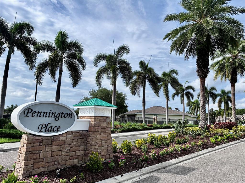 A stone monument sign for Pennington Place stands beside a road lined with palm trees — 9082 COACHMAN DRIVE, VENICE, FL
